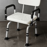 Shower chair positioned in a bathroom setting with visible water on the floor and seat